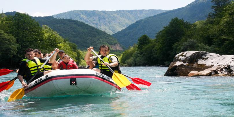 Group of students whitewater rafting on a river.