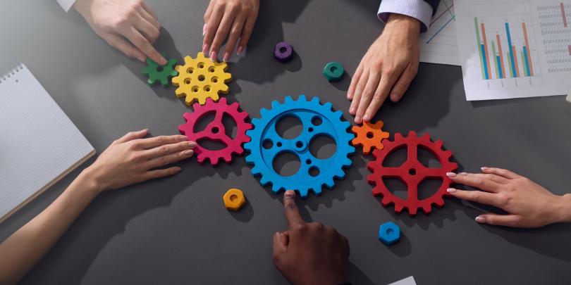 People's hands on gears to illustrate teamwork