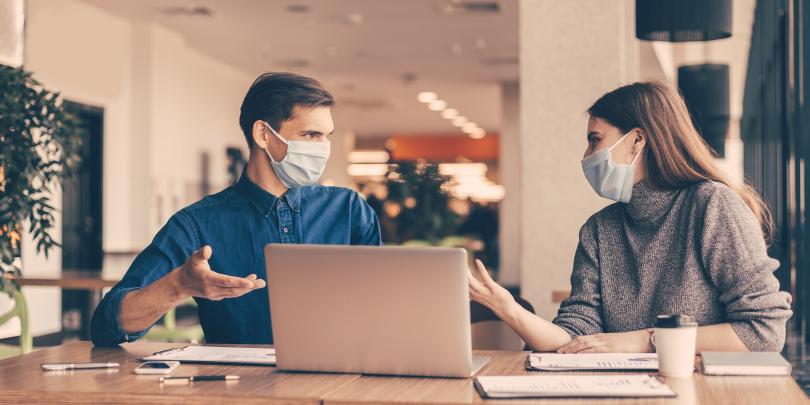 People in masks looking at a computer