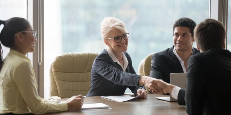 Female executive greeting someone at a table
