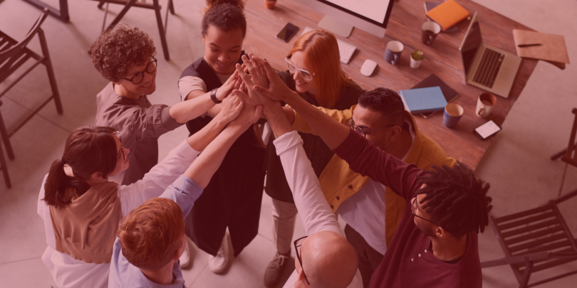 Diverse team huddle with everyones hands overlapping in the middle