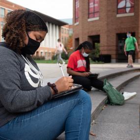 Students sitting on steps in front of Fisher Hall